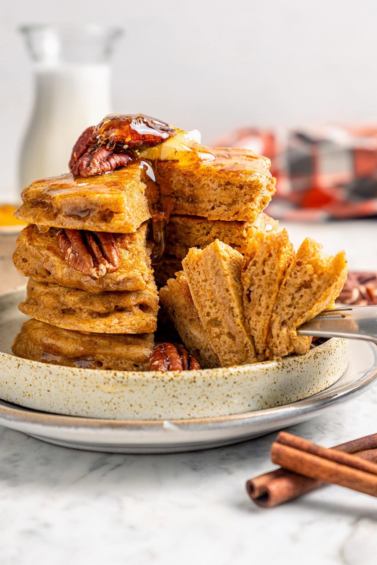 This lightened up version of pumpkin pancakes is also extra fluffy! You'll love the cozy fall flavor in this easy, healthier pancake recipe. Fork piercing stack of fluffy pumpkin pancakes on plate