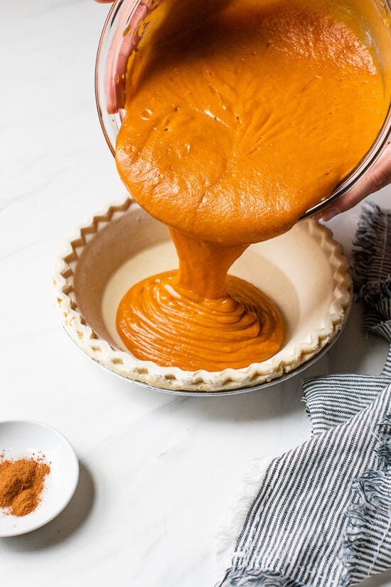 Still looking for the perfect Thanksgiving dessert? This easy, healthier version of the classic sweet potato pie recipe is always a hit! Pouring sweet potato filling into pie crust