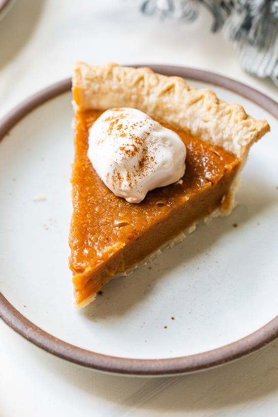 Still looking for the perfect Thanksgiving dessert? This easy, healthier version of the classic sweet potato pie recipe is always a hit! Slice of sweet potato pie on plate