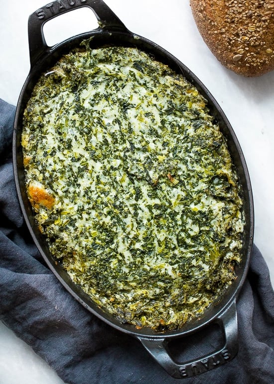 This cheesy hot spinach dip is perfect for parties! You can double or triple this lightened up recipe as needed and it’s always a hit. Overhead view of hot spinach dip in baking dish