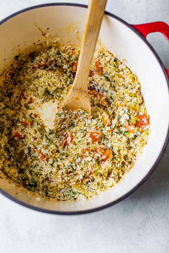Authentic Arroz Con Pollo, or Latin chicken and rice, is the ultimate one-pot meal. It’s a classic Latin dish that I grew up with and love! Browned rice and vegetables in a Dutch oven.