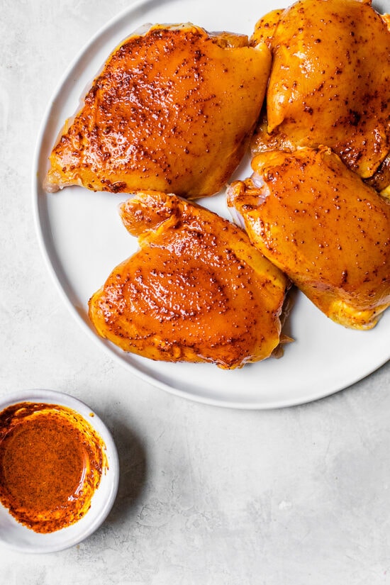 Authentic Arroz Con Pollo, or Latin chicken and rice, is the ultimate one-pot meal. It’s a classic Latin dish that I grew up with and love! Seasoned chicken thighs marinating on a plate.