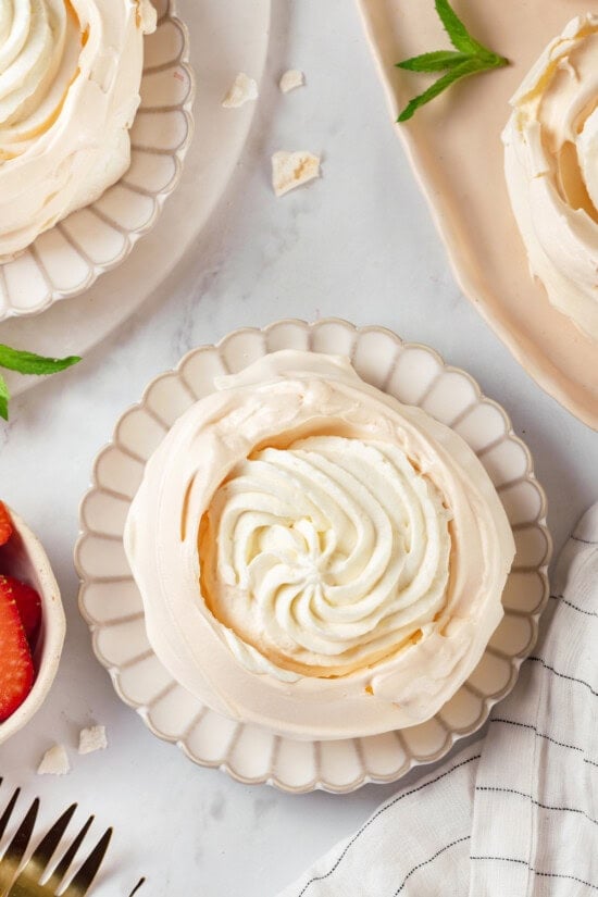 Pavlova is an elegant, light dessert that pairs airy meringue nests with whipped cream and fresh fruit. It's almost too pretty to eat! Overhead view of pavlova filled with whipped cream