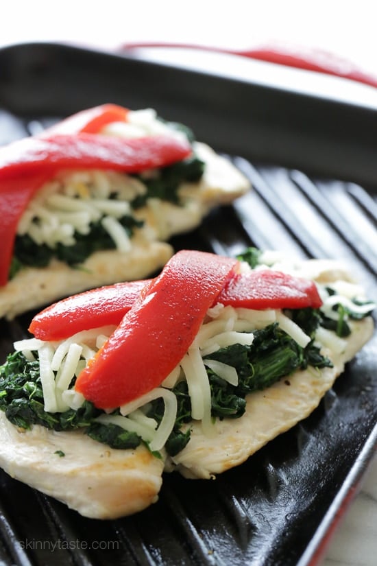 Grilled chicken on a grill pan topped with sauteed garlicky spinach, mozzarella and roasted peppers