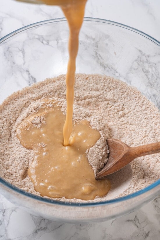A classic blueberry muffin recipe lightened up with whole wheat flour and applesauce in place of the oil. So moist and delicious! Pouring liquid ingredients into dry ingredients for muffins