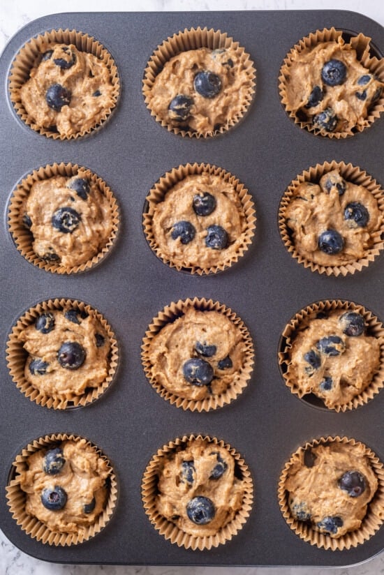 A classic blueberry muffin recipe lightened up with whole wheat flour and applesauce in place of the oil. So moist and delicious! Overhead view of blueberry muffin batter in pan