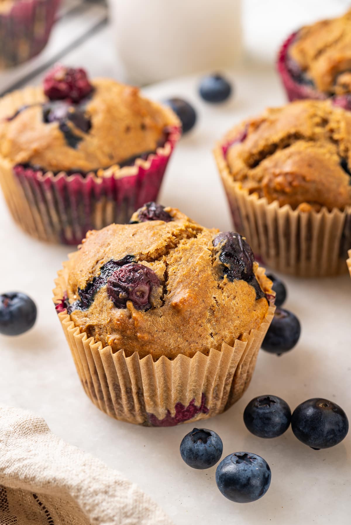 A classic blueberry muffin recipe lightened up with whole wheat flour and applesauce in place of the oil. So moist and delicious! Blueberry muffin made with whole wheat pastry flour, with additional muffins in background