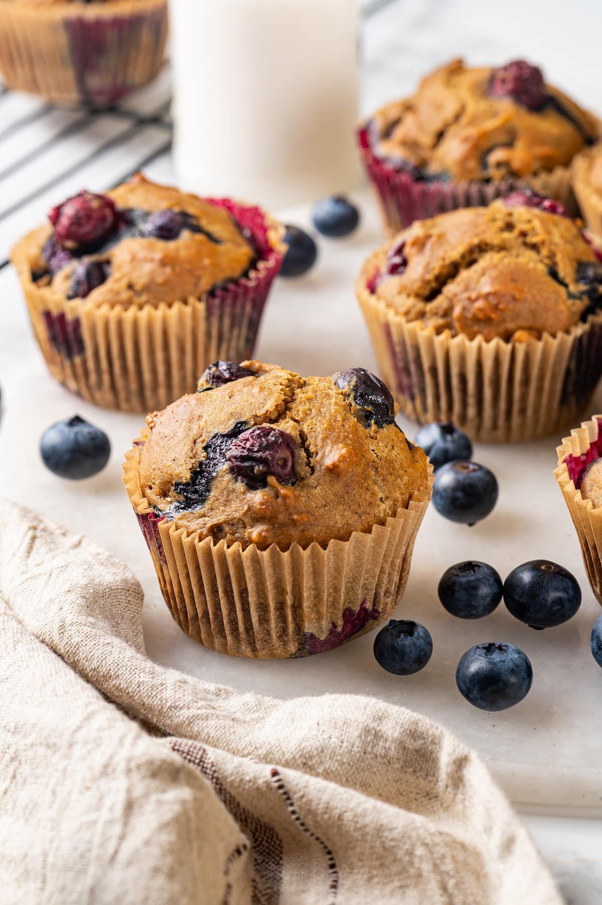 A classic blueberry muffin recipe lightened up with whole wheat flour and applesauce in place of the oil. So moist and delicious! Blueberry muffins on marble board with fresh berries