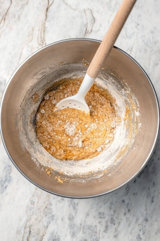 Chewy granola bars are so easy to make at home! This recipe is lighter than other versions and can be customized with your favorite mix-ins. Wet ingredients for granola bars in bowl with spoon.