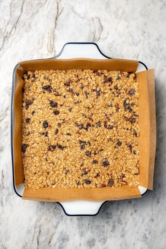 Chewy granola bars are so easy to make at home! This recipe is lighter than other versions and can be customized with your favorite mix-ins. Granola bars in pan before baking.