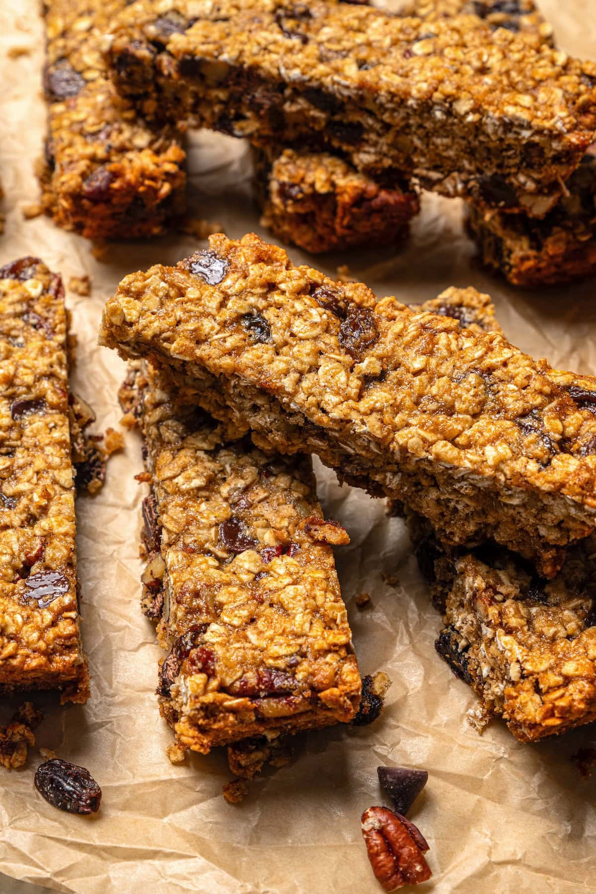 Chewy granola bars are so easy to make at home! This recipe is lighter than other versions and can be customized with your favorite mix-ins. Chewy granola bars piled on parchment paper.