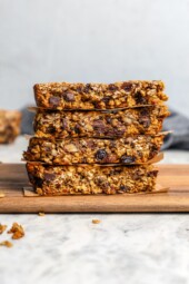 Stack of 4 chewy granola bars with chocolate chips, pecans, and raisins.