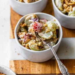 apple and grape fruit salad in a bowl with a spoon