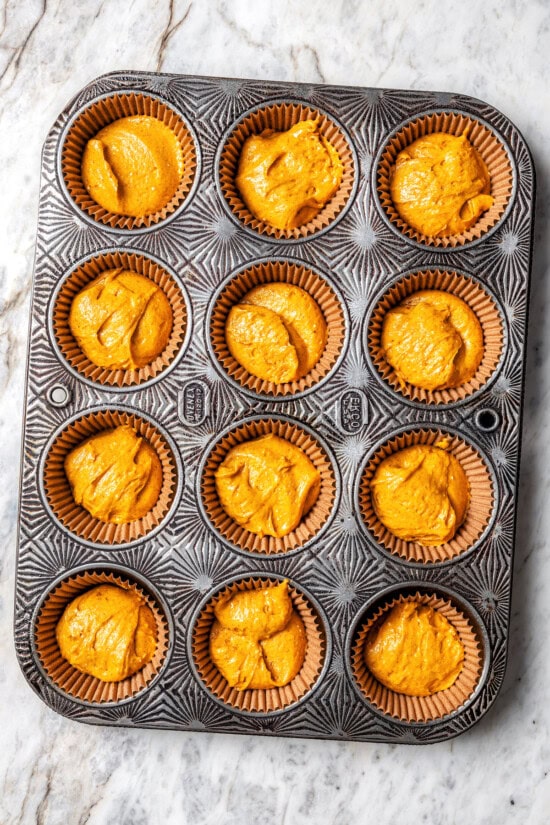 Boxed cake mix makes these pumpkin cupcakes easy to whip up for Halloween parties, Thanksgiving or anytime you want a cozy fall treat! Overhead view of batter in cupcake pan