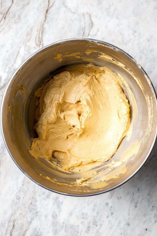 Boxed cake mix makes these pumpkin cupcakes easy to whip up for Halloween parties, Thanksgiving or anytime you want a cozy fall treat! Overhead view of pumpkin cream cheese frosting in bowl
