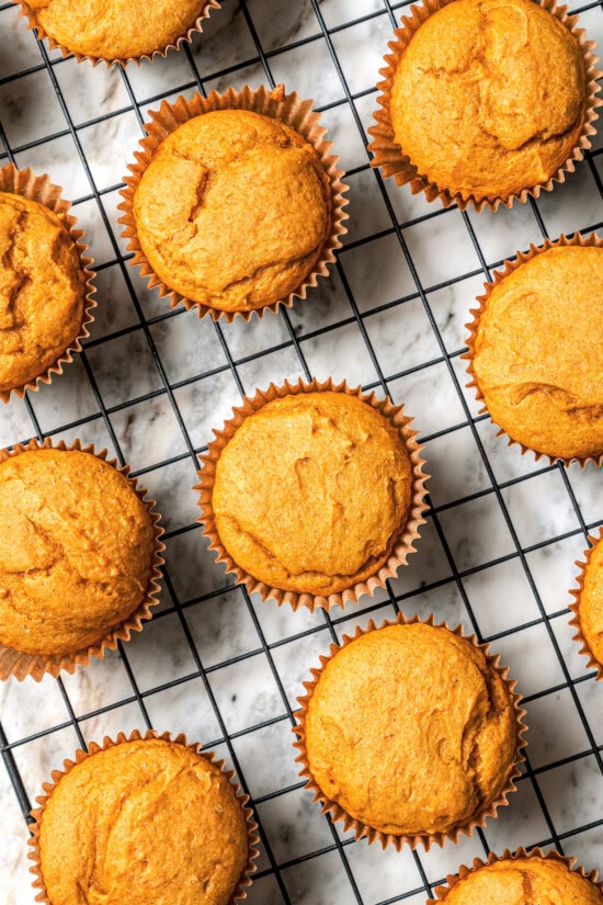 Boxed cake mix makes these pumpkin cupcakes easy to whip up for Halloween parties, Thanksgiving or anytime you want a cozy fall treat! Overhead view of pumpkin cupcakes on wire rack