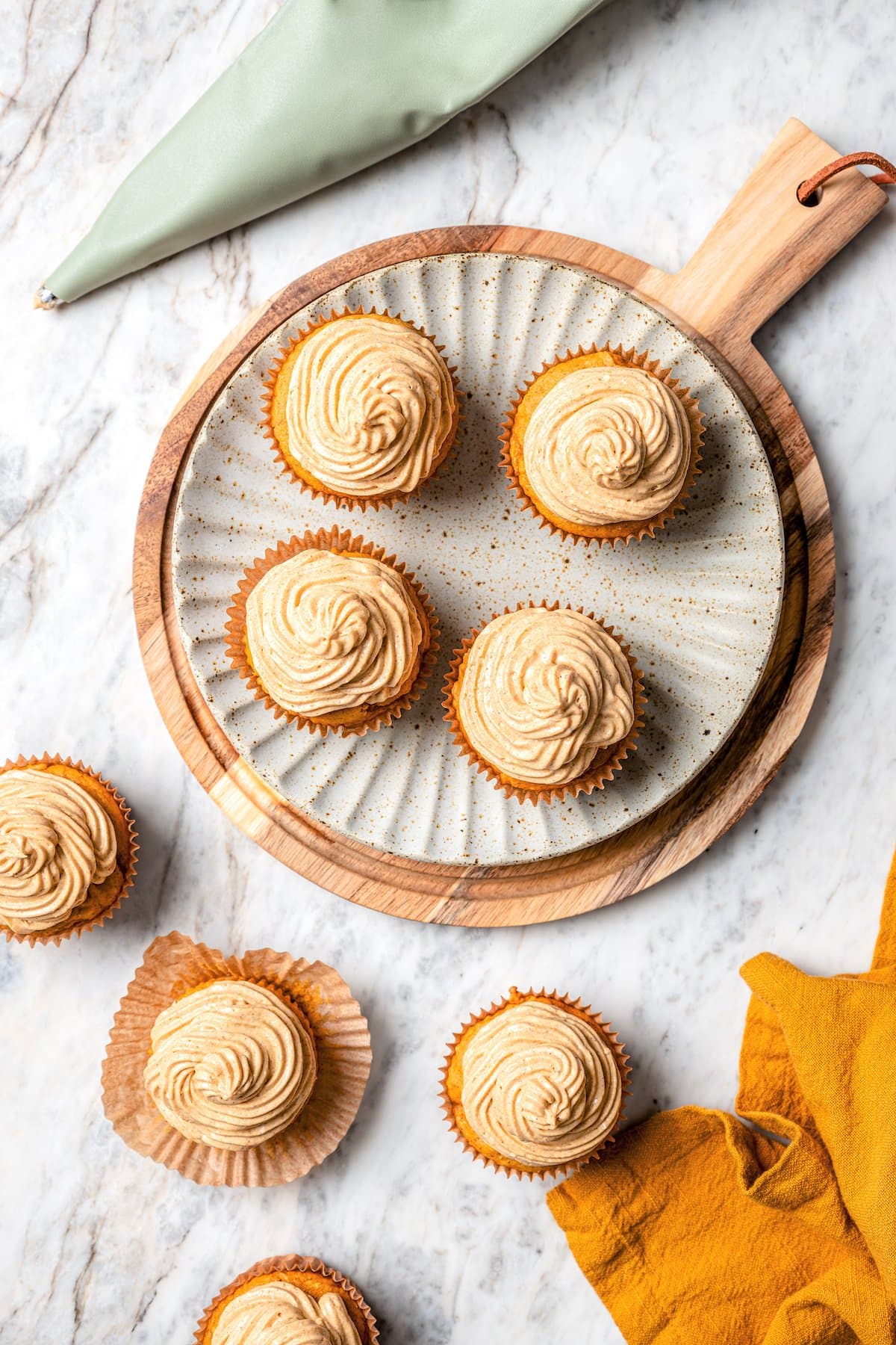 Boxed cake mix makes these pumpkin cupcakes easy to whip up for Halloween parties, Thanksgiving or anytime you want a cozy fall treat! Overhead view of pumpkin cupcakes with pumpkin spice frosting