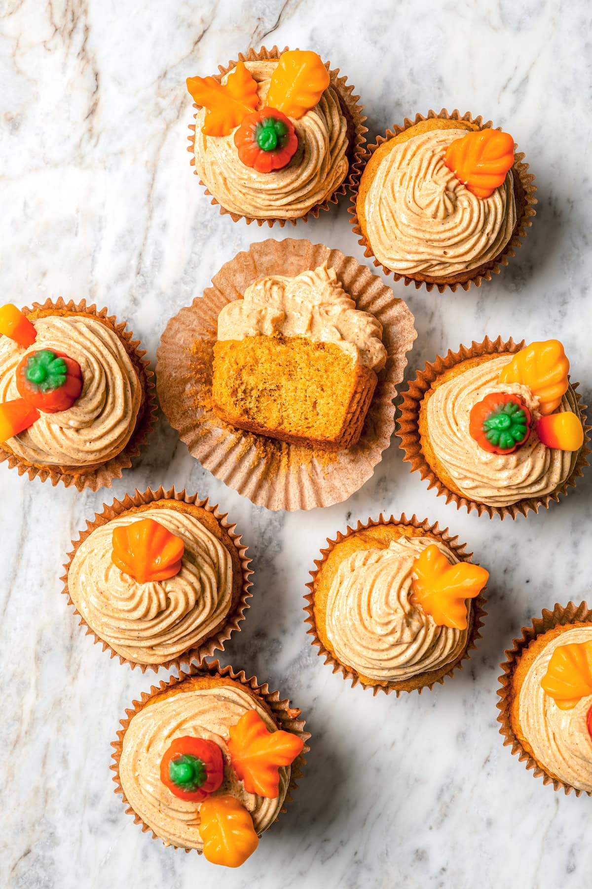 Boxed cake mix makes these pumpkin cupcakes easy to whip up for Halloween parties, Thanksgiving or anytime you want a cozy fall treat! Overhead view of pumpkin cupcakes on marble countertop