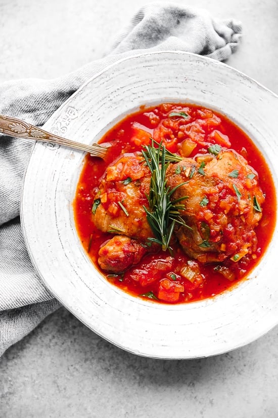 Pollo in Potacchio is an Italian braised chicken dish made with tomatoes, rosemary and garlic. The chicken cooks until it's fork tender, which is great served with pasta, noodles or polenta.
