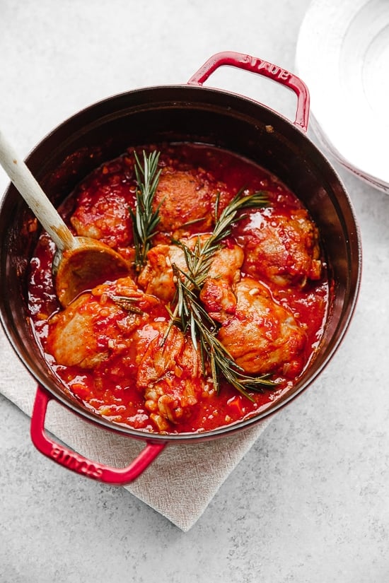 Pollo in Potacchio is an Italian braised chicken dish made with tomatoes, rosemary and garlic. The chicken cooks until it's fork tender, which is great served with pasta, noodles or polenta.