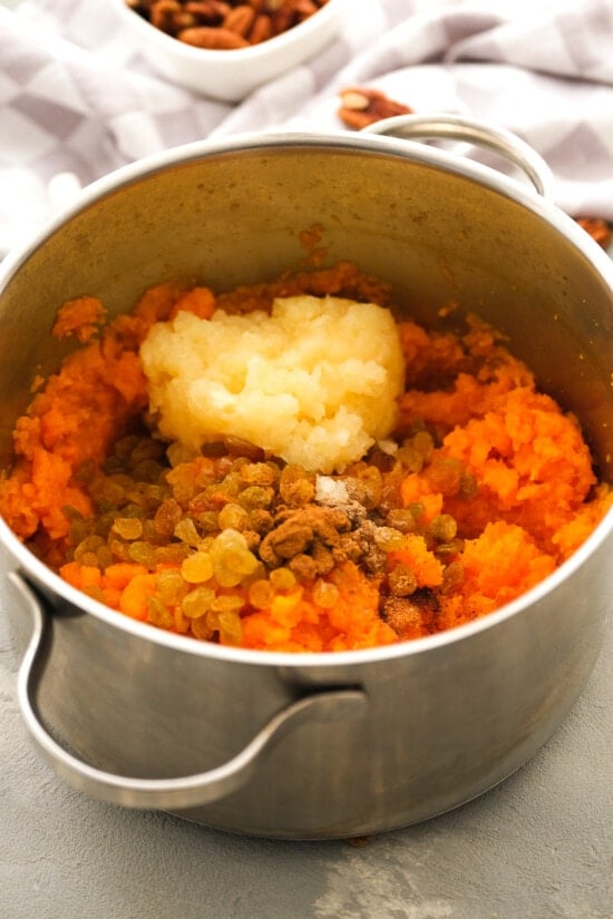 This lighter sweet potato casserole is made with golden raisins, crushed pineapple, and spices, topped with toasty marshmallows and pecans. Raisins, spices, and pineapple added to mashed sweet potatoes in a pot.