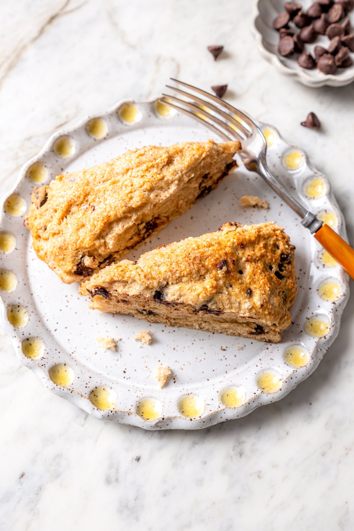 Chocolate chip scones are sweetened to perfection and studded with chocolate chips to make them taste like a treat. An easy no-fail recipe! Two chocolate chip scones on plate with fork