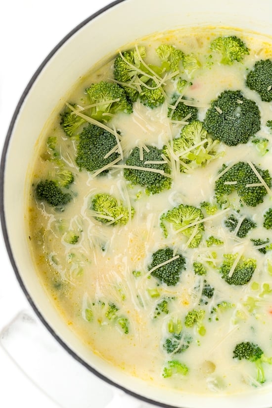 making soup with broccoli in a white pot.