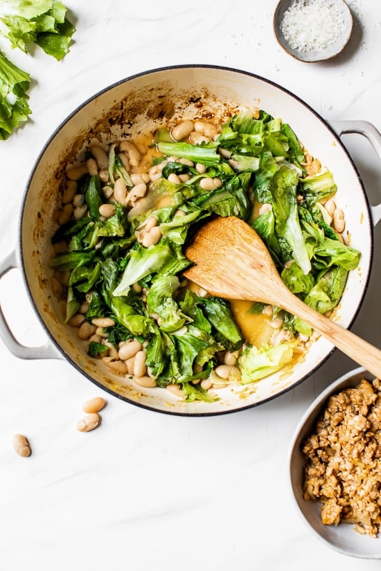 adding beans and escarole to a pot.