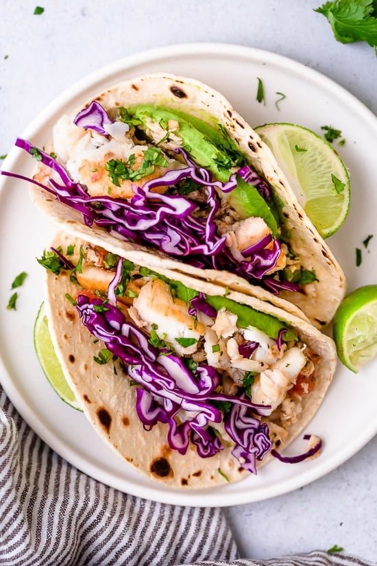 These easy Cilantro Lime Fish Tacos are made with flaky white fish, tomatoes, jalapeños, cilantro and lime topped with avocado.