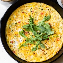 Caramelized onions and sautéed red bell peppers and zucchini mixed with eggs and Parmesan create a winning egg frittata breakfast dish.