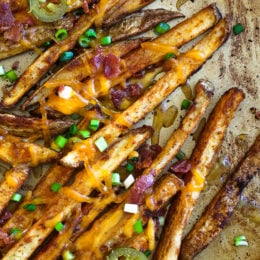 Guiltless cheesy baked seasoned fries topped with bacon, jalapeños and scallions... this is SOOO good! Pure comfort food when cheese fries are what you're craving.