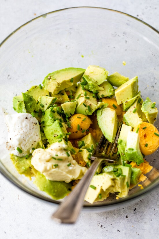 This avocado egg salad uses half the egg yolks and adds lots of healthy fats from avocado. An easy healthy, high protein lunch! hard boiled eggs and avocado in a bowl.