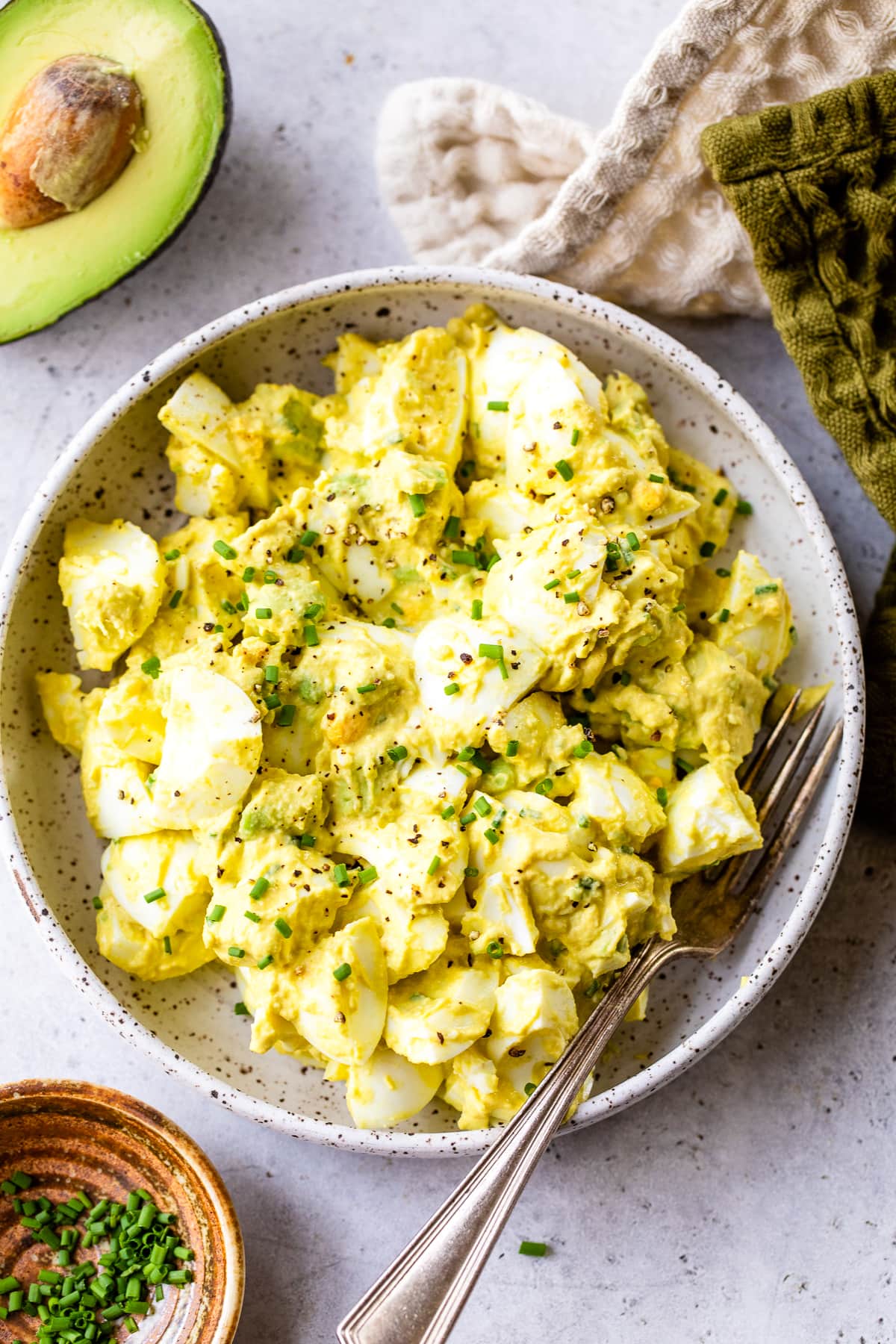 This avocado egg salad uses half the egg yolks and adds lots of healthy fats from avocado. An easy healthy, high protein lunch! Avocado Egg Salad in a bowl with a fork.