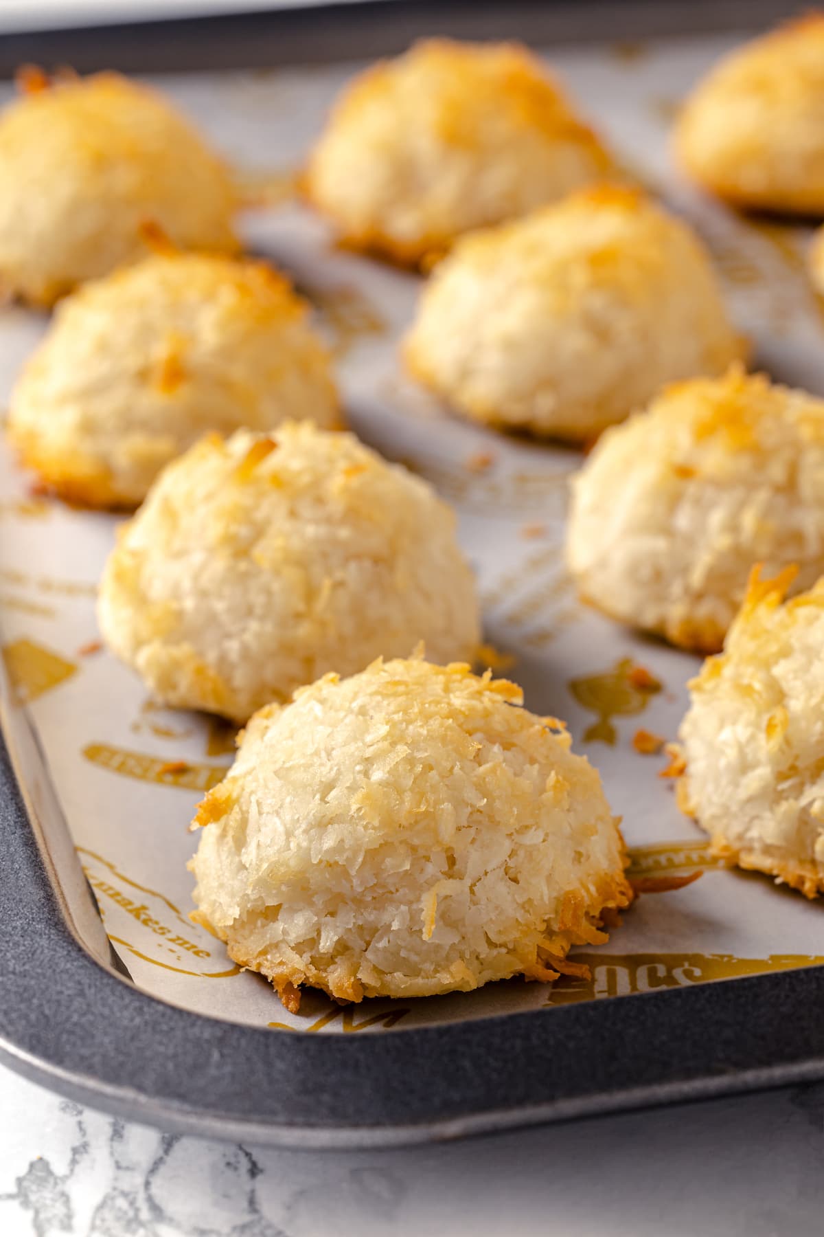 Made with sweetened coconut flakes, egg whites, and just a few other ingredients, Coconut Macaroons are moist, chewy, and perfectly flavored. Close up of coconut macaroons on a baking sheet
