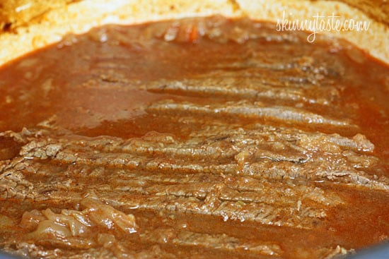 This braised brisket recipe is slow cooked in the oven with potatoes, carrots and onions. Slicing it half-way through makes it extra tender! Braised brisket in gravy.