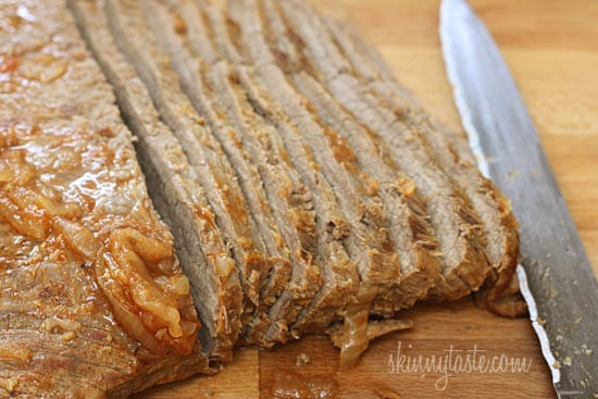 This braised brisket recipe is slow cooked in the oven with potatoes, carrots and onions. Slicing it half-way through makes it extra tender! Sliced brisket on cutting board with knife.