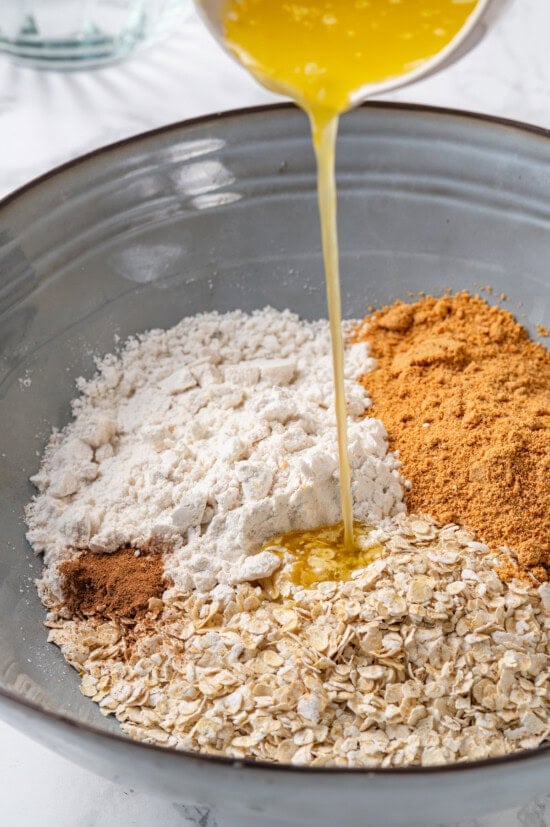 Honey adds the perfect amount of sweetness to the filling in this strawberry rhubarb crisp recipe. Easy to make and impossible to resist! Pouring melted butter into ingredients for crisp topping