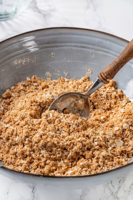 Honey adds the perfect amount of sweetness to the filling in this strawberry rhubarb crisp recipe. Easy to make and impossible to resist! Crisp topping in bowl with spoon