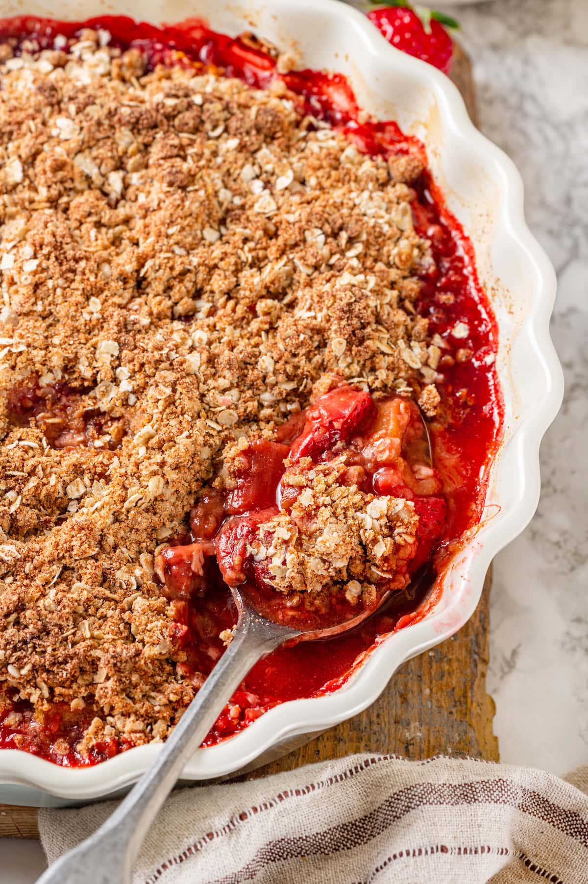 Honey adds the perfect amount of sweetness to the filling in this strawberry rhubarb crisp recipe. Easy to make and impossible to resist! Baking dish with strawberry rhubarb crisp with spoon scooping out serving