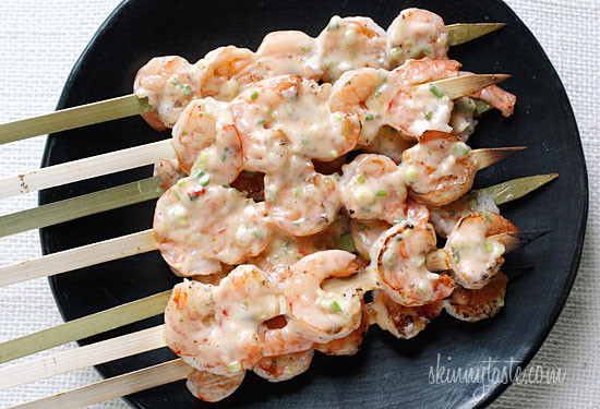 A plate of grilled shrimp on skewers with creamy chili sauce