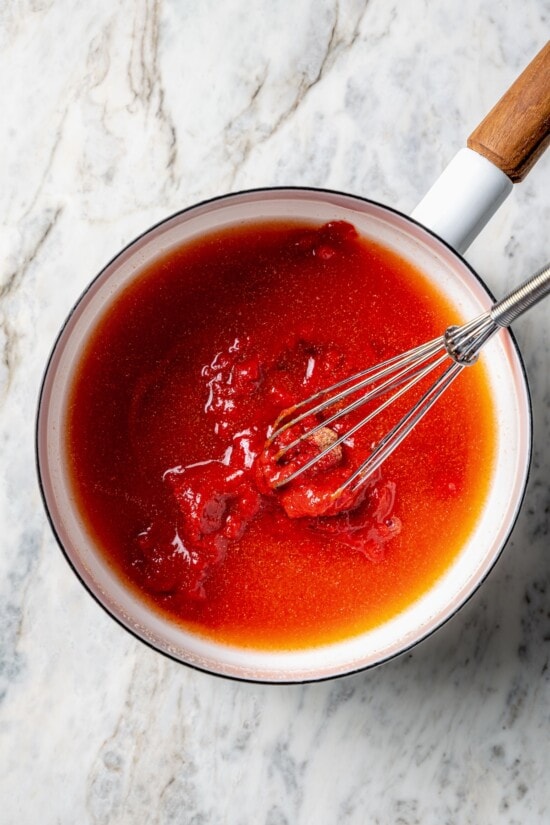 A healthy recipe for homemade ketchup with no high fructose corn syrup. Instead it's sweetened naturally with honey and it tastes amazing! Overhead view of ingredients for homemade ketchup in saucepan with whisk
