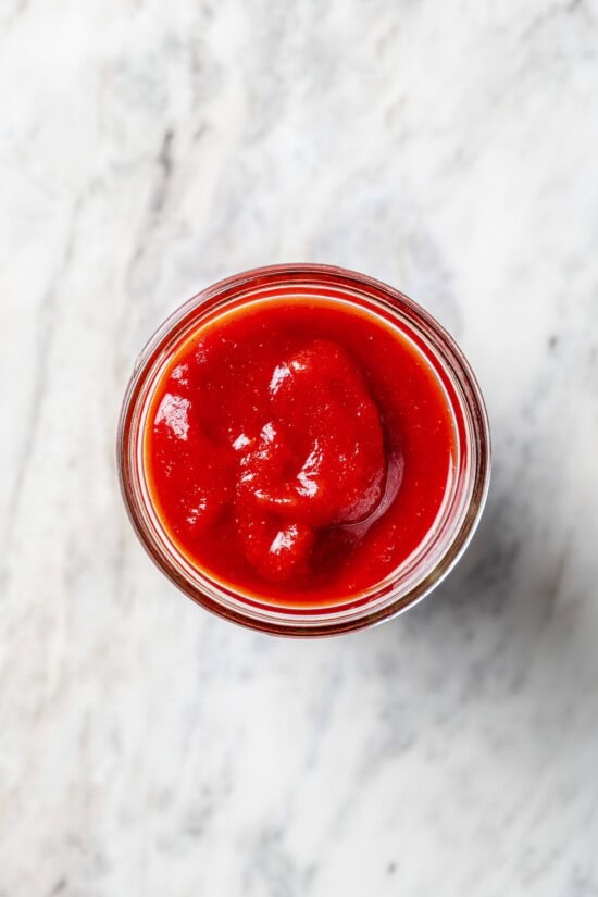A healthy recipe for homemade ketchup with no high fructose corn syrup. Instead it's sweetened naturally with honey and it tastes amazing! Overhead view of homemade ketchup in jar