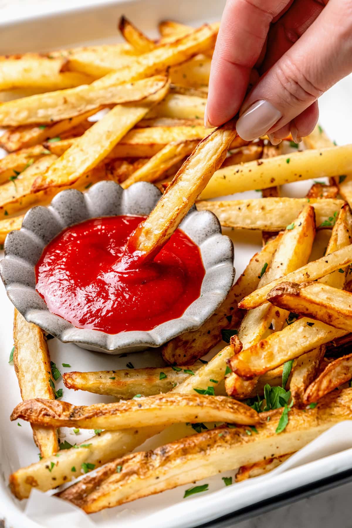 A healthy recipe for homemade ketchup with no high fructose corn syrup. Instead it's sweetened naturally with honey and it tastes amazing! Hand dipping fry into bowl of homemade ketchup