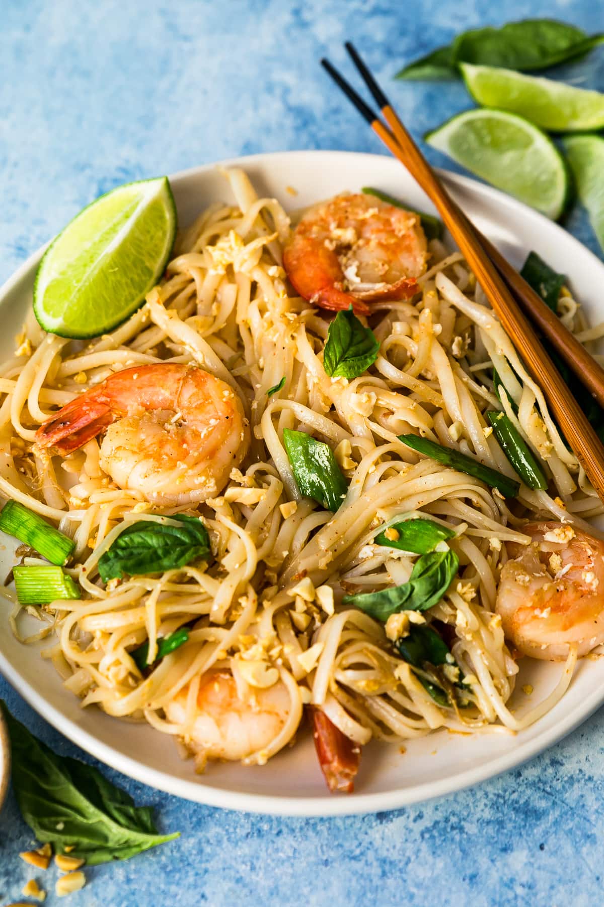 This easy homemade Pad Thai recipe is a lightened up version of the original made with shrimp, eggs, and tofu. Dinner’s done in 25 minutes! Pad Thai with shrimp on white plate with chopsticks