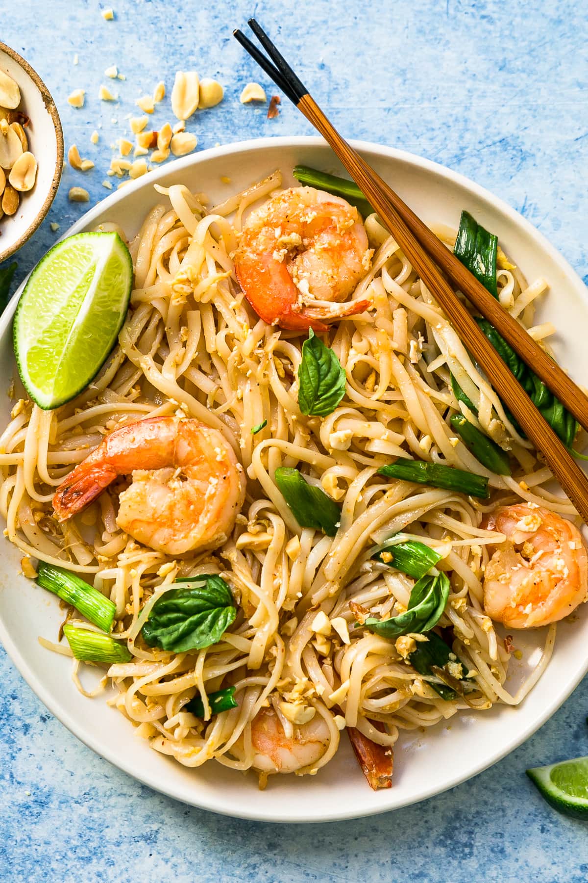This easy homemade Pad Thai recipe is a lightened up version of the original made with shrimp, eggs, and tofu. Dinner’s done in 25 minutes! Overhead view of homemade Pad Thai in bowl with chopsticks