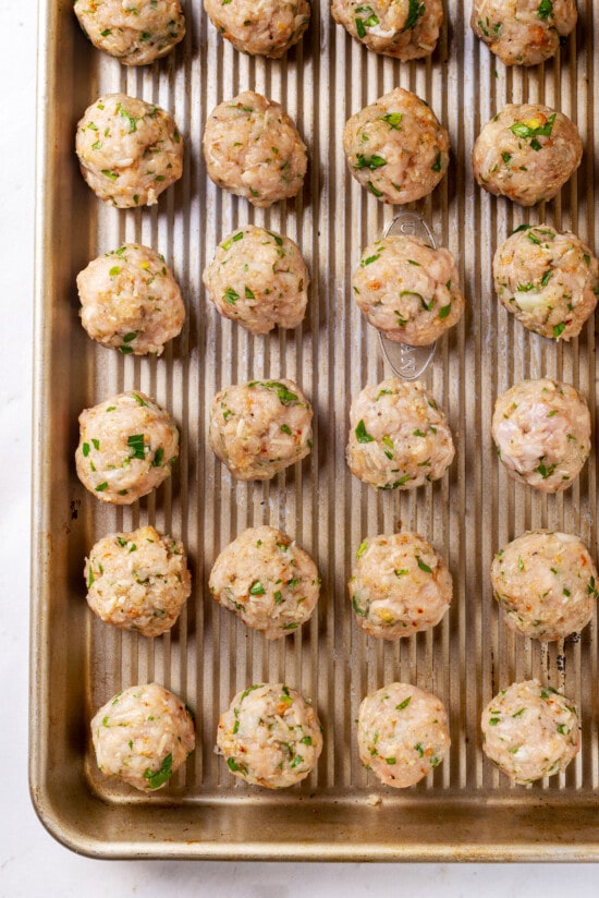 Made with homemade turkey meatballs, tiny pasta, and dark leafy greens, Italian Wedding Soup is simple yet flavorful. Ready in 30 minutes! Mini turkey meatballs on a baking sheet