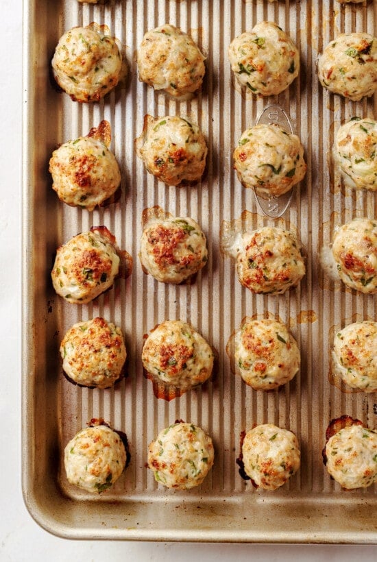 Made with homemade turkey meatballs, tiny pasta, and dark leafy greens, Italian Wedding Soup is simple yet flavorful. Ready in 30 minutes! Cooked mini turkey meatballs on a baking sheet