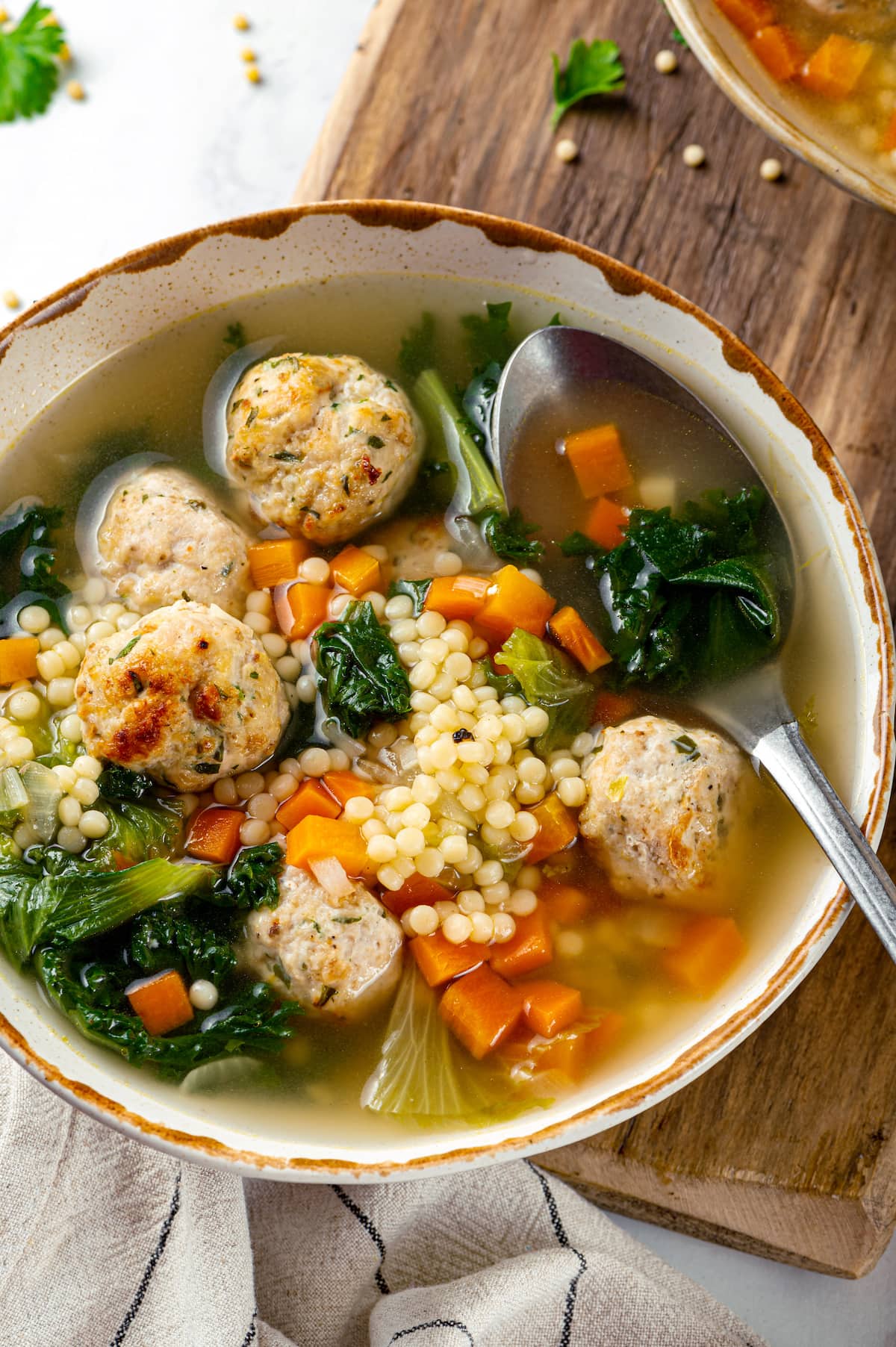 Made with homemade turkey meatballs, tiny pasta, and dark leafy greens, Italian Wedding Soup is simple yet flavorful. Ready in 30 minutes! A bowl of Italian wedding soup with a spoon