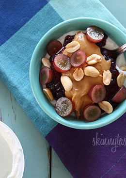 Peanut butter, grape jam, peanuts, and fresh red grapes on top of a bowl of yogurt... who needs the bread!