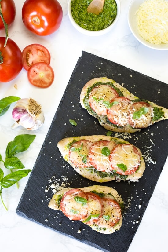 This easy Baked Pesto Chicken is a fast chicken dish made with skinless chicken breasts, pesto, tomatoes, mozzarella and Parmesan cheese. You can make this in the oven, or make it outside on the grill!